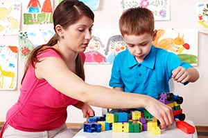 Female teacher and boy playing w blocks