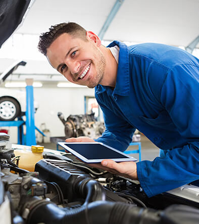 smiling auto service technician checking engine under a car hood