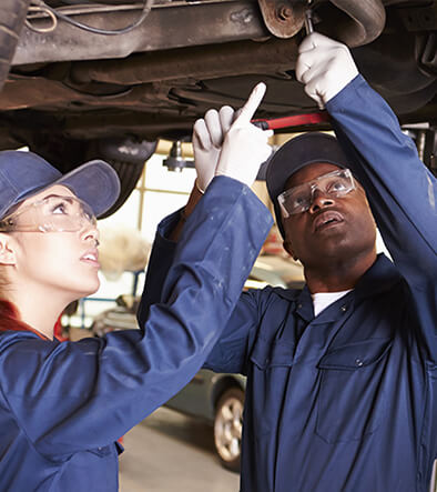 automotive service techs working beneath a car