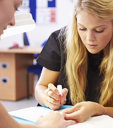 cosmotologist applying polish to a woman's nails