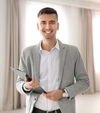 smiling real estate agent inside a room, holding a clipboard 